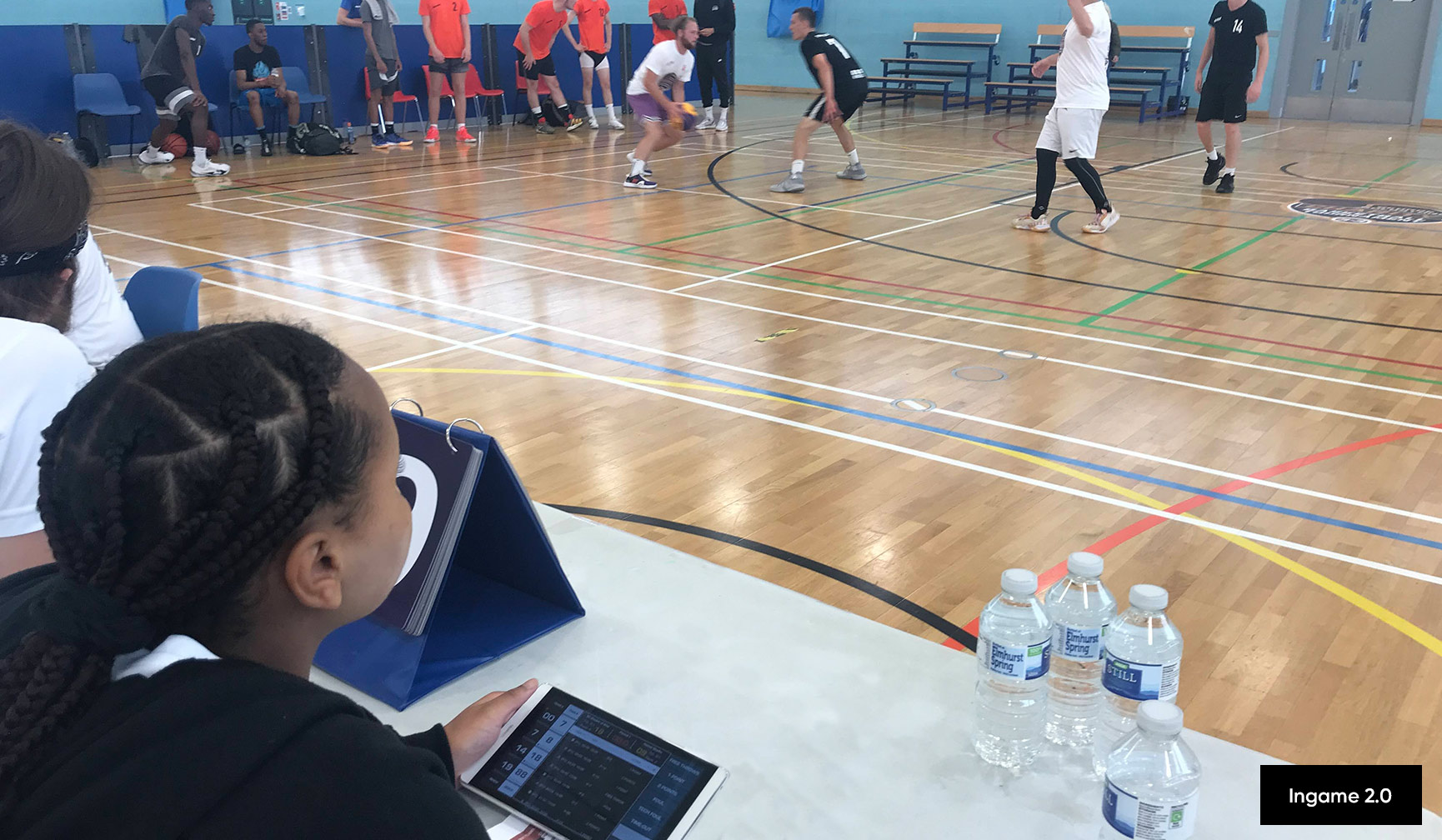 ein Mädchen beobachtet das Basketballspiel am Kampfgericht mit einem digitalen Spielbericht